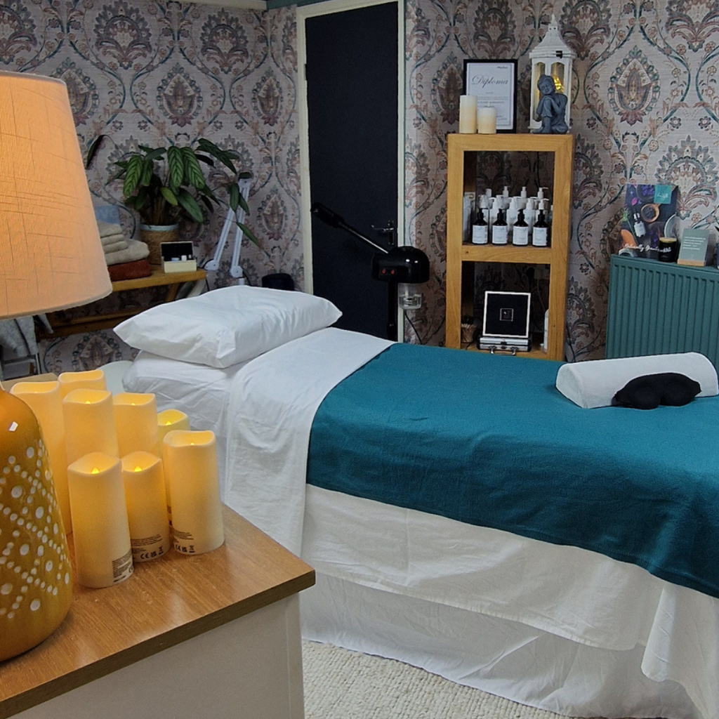 Relaxing Reiki therapy room in Tewkesbury with treatment couch, candlelight, blankets, and wellbeing décor designed to support relaxation and stress relief.